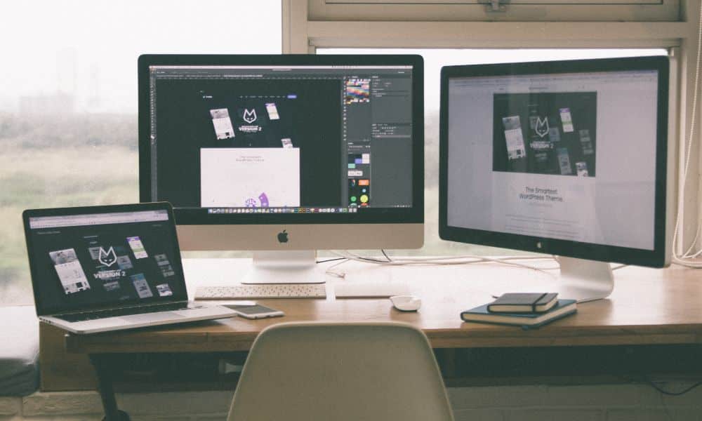 Three computers on a wooden desk