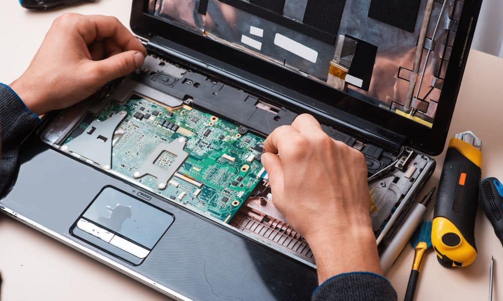 Person repairing a laptop motherboard.