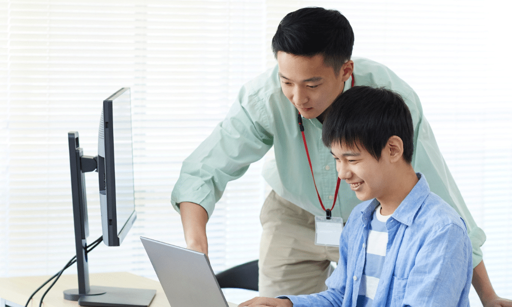 Instructor assisting student with laptop