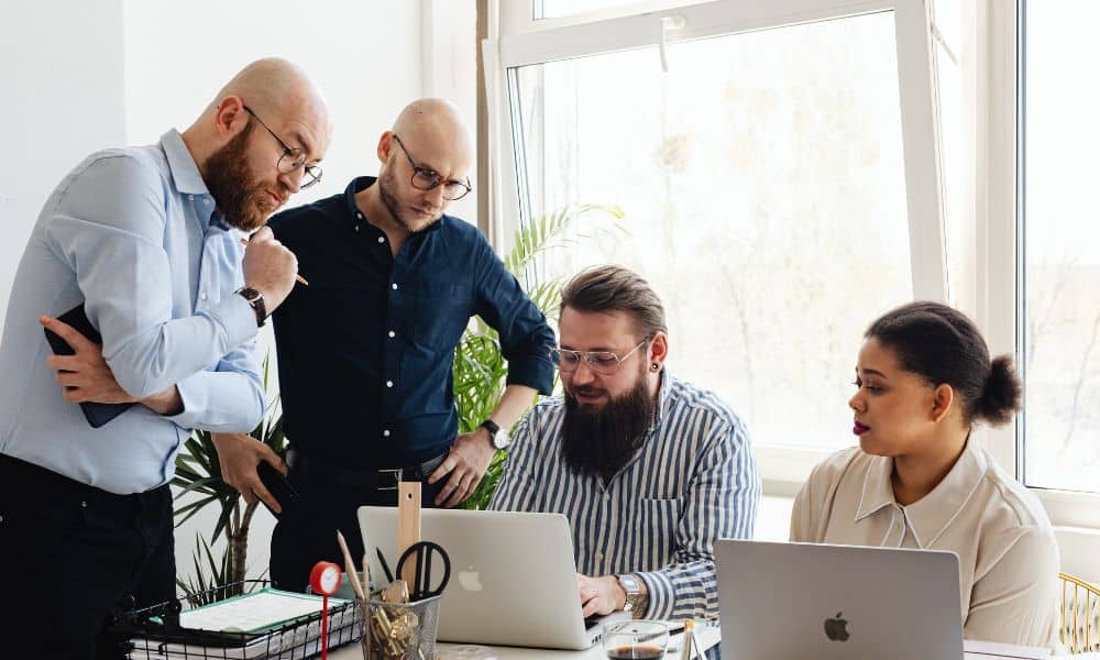 Group collaborating around laptops in office.